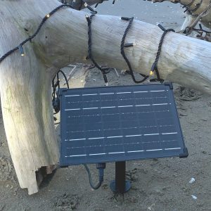 A small solar panel with PW/WW fairy lights on the beach